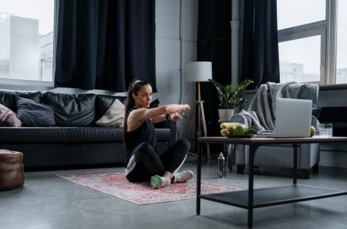 Woman doing exercise at home, sitting and stretching in a cozy living room.