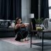 Woman doing exercise at home, sitting and stretching in a cozy living room.